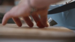 A person is using a knife to cut a tomato on a wooden cutting board. The knife is positioned on the cutting board, and the tomato is being sliced - Powered by Shutterstock - Get 15% off with code: PIKWIZARD15