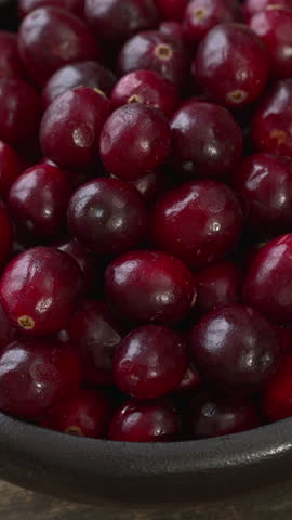 Close-up view of fresh cranberries in a bowl. Table spin, selective focus, vertical video.