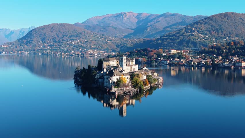 Aerial view of the picturesque Isola San Giulio island, showcasing its historic buildings reflected in the tranquil water, Isola San Giulio, Piemonte, Italy.