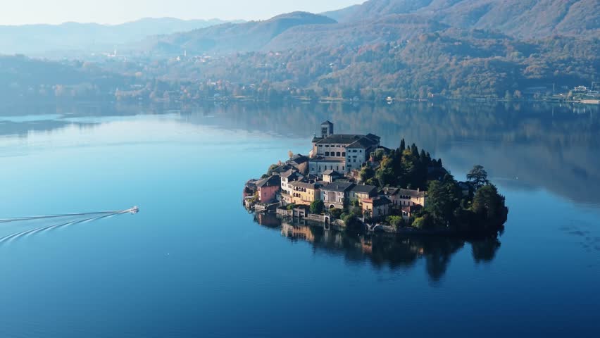 Aerial view of Isola San Giulio, a charming island with historic buildings, surrounded by the tranquil blue waters of Lake Orta, Isola San Giulio, Piemonte, Italy.