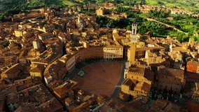 A breathtaking aerial shot of Siena at sunrise. The golden morning light illuminates the ancient rooftops and the famous Piazza del Campo, nestled in the Tuscan hills. - Powered by Shutterstock - Get 15% off with code: PIKWIZARD15