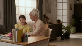 Teenage girl discussing homework task with cheerful grandmother and mother while using laptop at desk cluttered with books in cozy bedroom - Powered by Shutterstock - Get 15% off with code: PIKWIZARD15