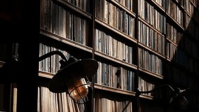 A warm desk lamp illuminates stacked books inside a quiet library, creating a cozy, scholarly atmosphere perfect for themes of learning, reading, knowledge, and academic study. - Powered by Shutterstock - Get 15% off with code: PIKWIZARD15