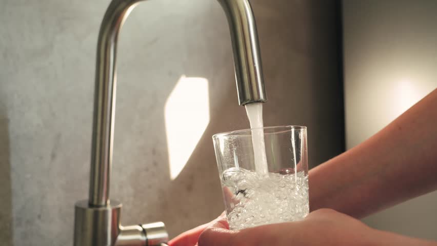Woman pouring tap water into glass, pure drinking water concept. High quality 4k footage