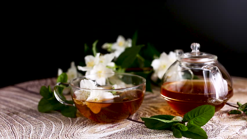 Green tea with jasmine in a glass teapot on a black background