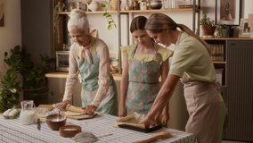 Girl child in apron putting parchment sheet on baking tray learning homemade cookies recipe from mother while granny preparing dough with rolling pin in cozy kitchen at weekend - Powered by Shutterstock - Get 15% off with code: PIKWIZARD15