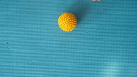 Female feet are doing foot exercises by rolling a prickly massage yellow ball under the foot on the yoga mat pressing down in different sides. Training to correct and relax the foot fascia. 4k footage - Powered by Shutterstock - Get 15% off with code: PIKWIZARD15