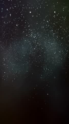 shimmering snow particles illuminated by ambient light in a nighttime setting, vertical video, slow motion