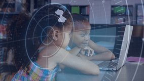 Two girls leaning over laptop in library, screen making HUD overlay pointing, smiling and learning. Education, classroom, students, children, collaboration, teamwork, technology - Powered by Shutterstock - Get 15% off with code: PIKWIZARD15