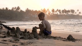 Silhouette of happy little boy building sandcastle on tropical beach at sunset. Golden sunlight reflecting on ocean waves and palm trees creating beautiful scenic backdrop - Powered by Shutterstock - Get 15% off with code: PIKWIZARD15