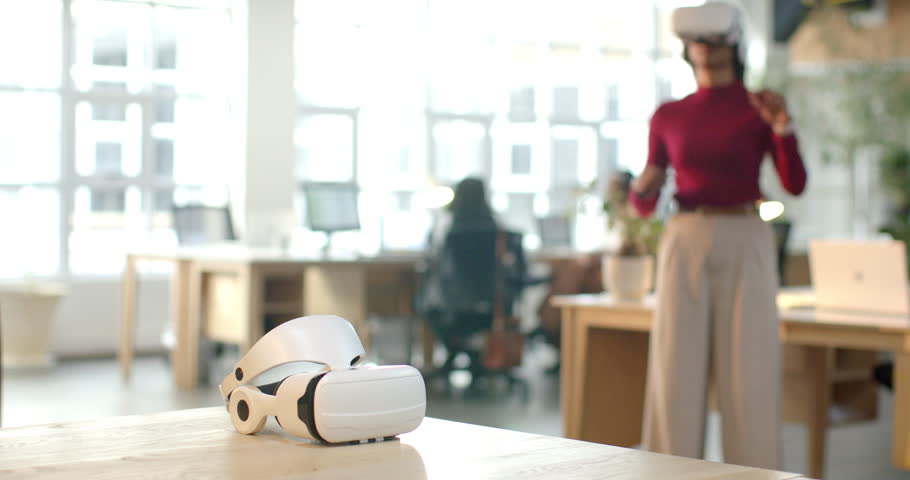 African American woman with VR headset clenching fists, navigating virtual interface at office desk. Virtual reality, technology, innovation, digital, futuristic, workspace, collaboration