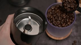 Close up. Woman's hands using a black spoon to pour aromatic roasted coffee beans into a coffee grinder from a transparent glass. Oatmeal cookies on a wooden board. Coffee preparation. Dark background - Powered by Shutterstock - Get 15% off with code: PIKWIZARD15