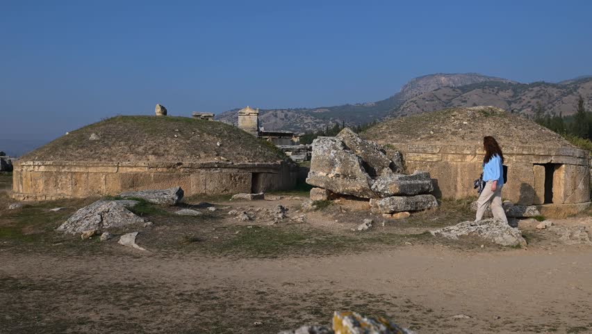 A woman walking beside the monumental tombs (tumuli) in ancient Hierapolis. Ancient city tour.