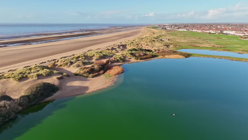 A view over Crosby beach towards the Irish Sea seen over Crosby Lake and the sand dunes on the start of the Sefton coastline.