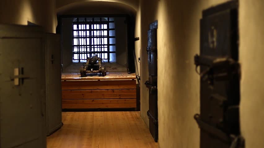 Dark stone prison inside a medieval castle, rusty bars, chains, and torch light illuminating the cold walls. Historical architecture and atmosphere of old confinement captured in 4K ultra HD.