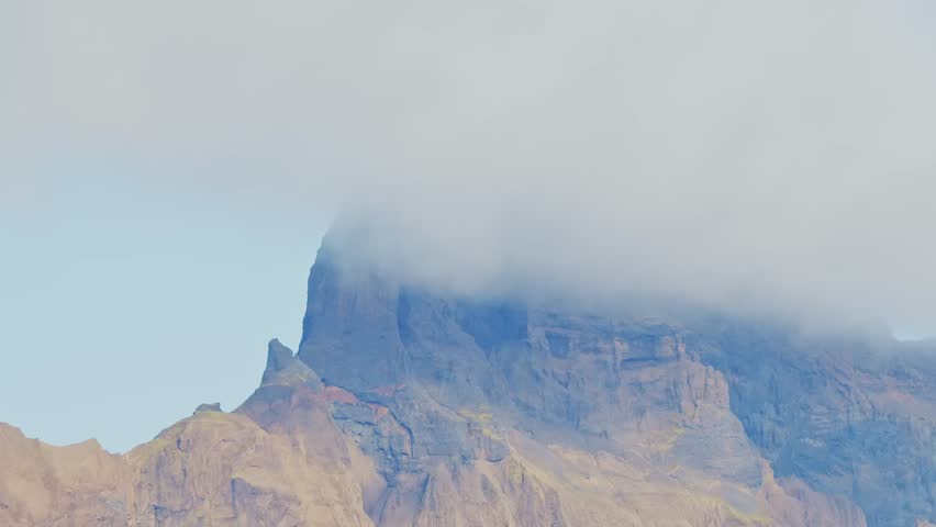 A dramatic landscape view of the Drakensberg Mountains, a UNESCO World Heritage Site in South Africa, with rugged cliffs and a cloud inversion blanketing the peaks.