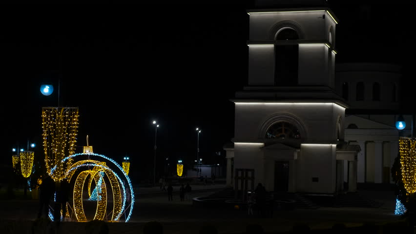 Cathedral bell tower at night with christmas decorations. Soft golden christmas lights adorning pine branch, blurred cathedral bell tower glowing against dark night sky, creating festive atmosphere