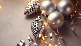 Christmas background, lights, garland, cone shaped and round silver baubles. Christmas border art design in beige color, top view. Winter holiday greeting card.  - Powered by Shutterstock - Get 15% off with code: PIKWIZARD15