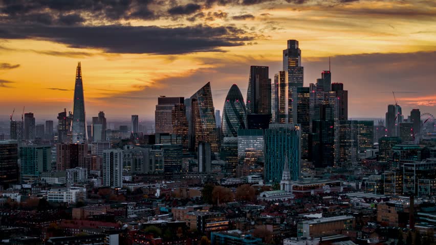 Aerial hyper lapse view of the illuminated, financial skyscrapers and the skyline at the City of London, England, during dusk