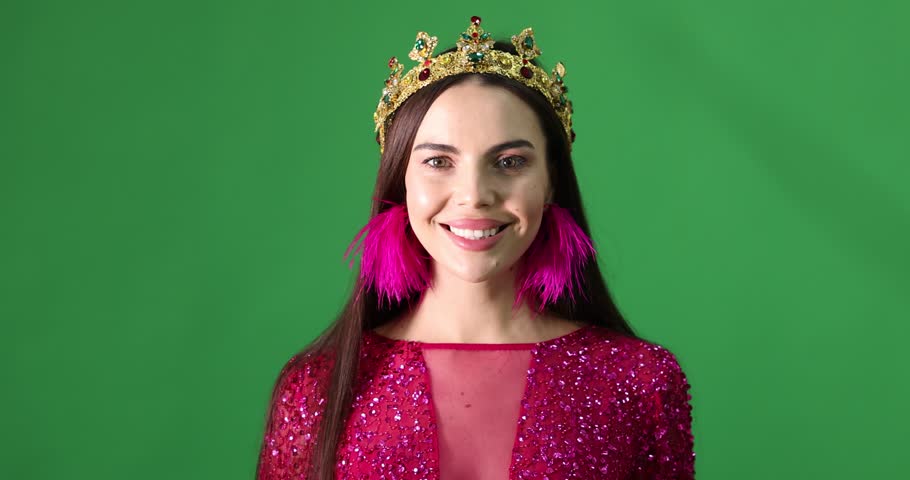 Beautiful woman wearing luxury crown under falling confetti on green background