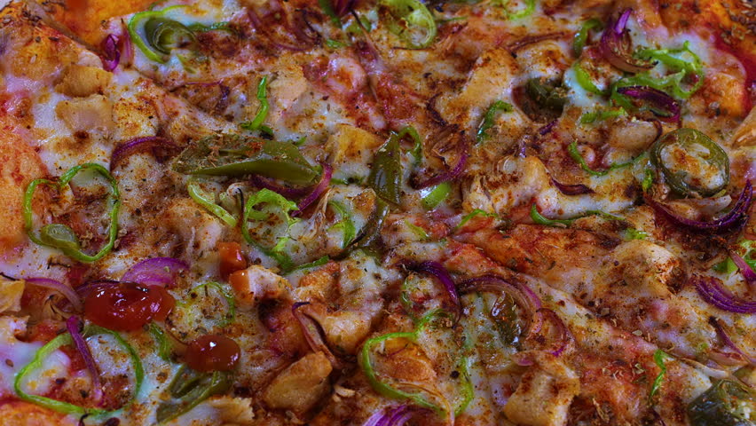Close-up of a hot baked pizza as ketchup is drizzled over melted cheese, chicken and vegetables. Premium food footage ideal for commercials, restaurant branding and delivery promos.