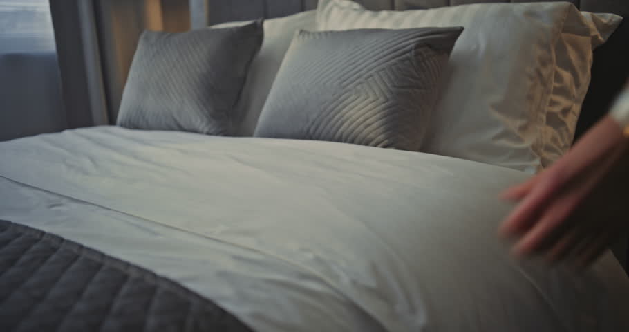 Hotel Female Worker Beside Bed, Carefully Making Linens Ensuring Neat Presentation Bedding. Concept Daily Housekeeping Routine, Hospitality Care, Hotel Standards For Cleanliness and Guest Experience.