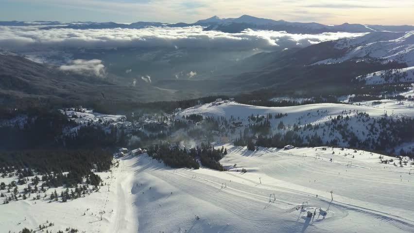 Snowy mountain landscape over looking a vast valley at sunset in winter