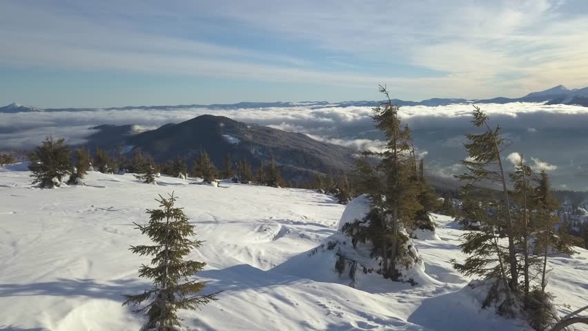 Winter landscape view of snow-covered mountains and clouds under blue sky