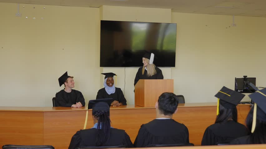 A young woman stands at the lectern and delivers a graduation speech to her classmates. 