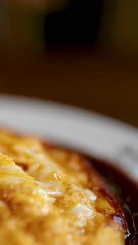 Close-up of fork lifting cheesy omurice, gooey cheese stretching, warm restaurant lighting, shallow focus