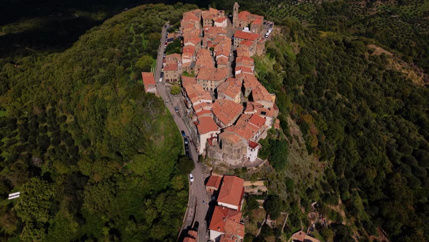 Montegiovi old town above fields and forested hills in Tuscany. Traditional stone houses aerial.