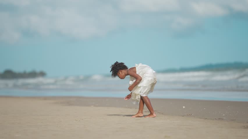 A little girl enjoying her holiday by searching for marine life crabs or shells on the seashore. Discovery of beachcombing, Leisure enjoying the weekend concept