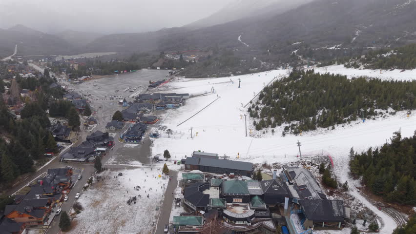 Drone flying backward revealing the base of Cerro Catedral ski resort in San Carlos de Bariloche, Río Negro Province, Argentina, during snowfall.