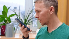 The man works from home and records a voice message on his smartphone - Powered by Shutterstock - Get 15% off with code: PIKWIZARD15