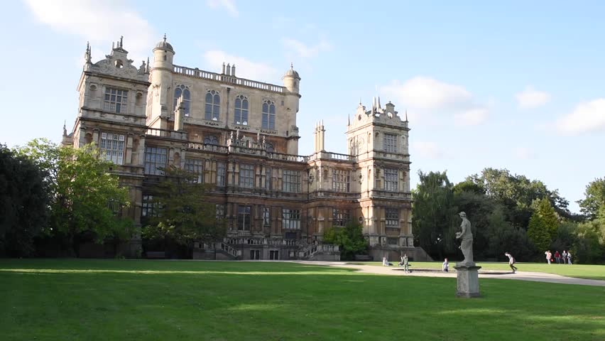 View of people walking through Wollaton Park in Nottingham, England, with the magnificent Wollaton Hall in the background. The Wollaton Hall is one of Nottingham’s most famous historic landmarks.