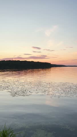 A peaceful walk on sunset unfolds along the Ternopil Pond in Ternopil, Ukraine, where calm waters and lush surroundings create a serene urban retreat.