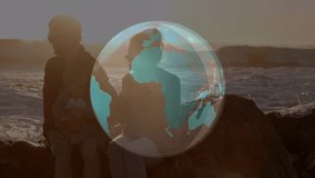 Couple holding baby on rock at sunset globe overlay rotating over ocean obscuring them for travel. Family, seaside, dusk, backlit, silhouettes, horizon, waves - Powered by Shutterstock - Get 15% off with code: PIKWIZARD15