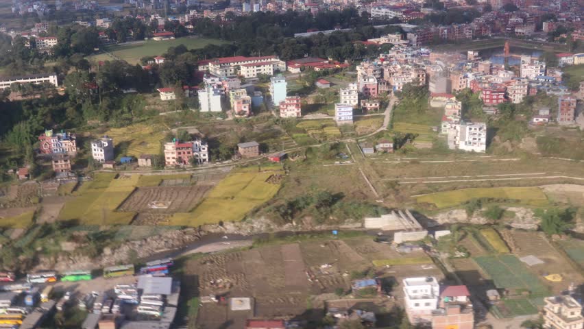 Kathmandu city and valley hills viewed from flying helicopter featuring urban landscape, green slopes, hazy sky and wide aerial scenery representing Nepal environment and mountain region landform spot