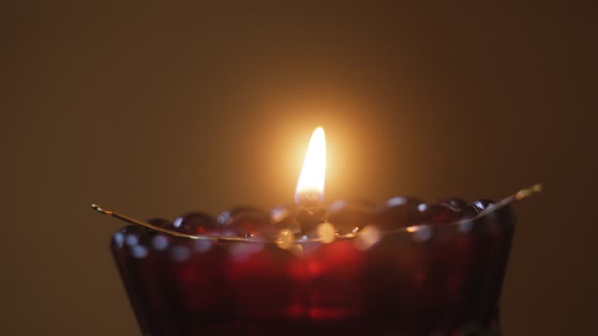 Burning candle flame in red glass holder with warm light, transition from sharp focus to soft blur, cinematic macro shot symbolizing calmness, meditation and cozy evening atmosphere in low light - Powered by Shutterstock - Get 15% off with code: PIKWIZARD15
