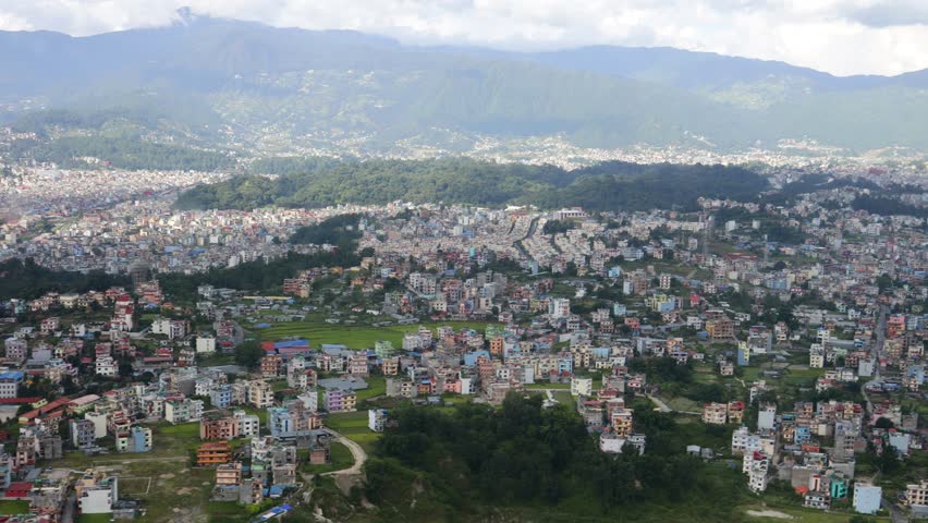 Kathmandu city and valley hills viewed from flying helicopter featuring urban landscape, green slopes, hazy sky and wide aerial scenery representing Nepal environment and mountain region landform spot