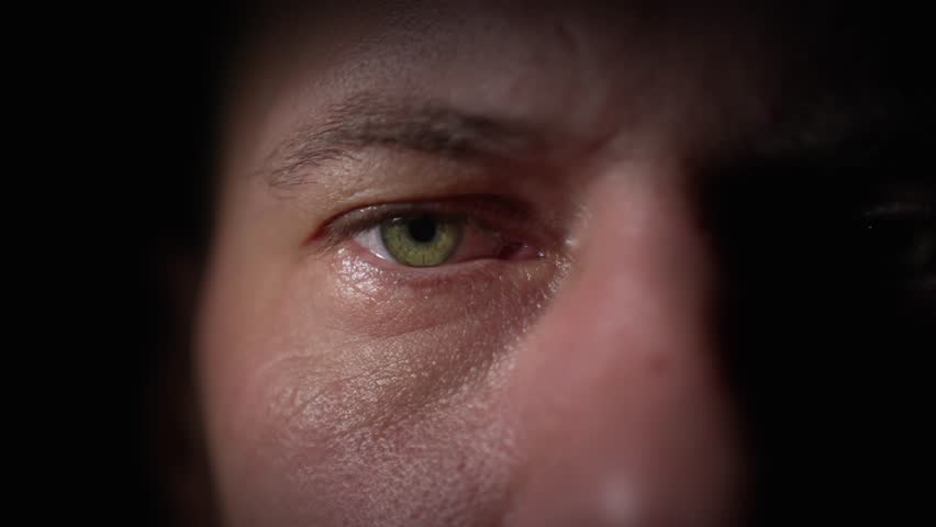 Close up portrait of caucasian bald man who opens his eyes and looks at the camera with tired, indifferent look with partial beam of lighting on his eyes. selective focus. Emotionless look of person.