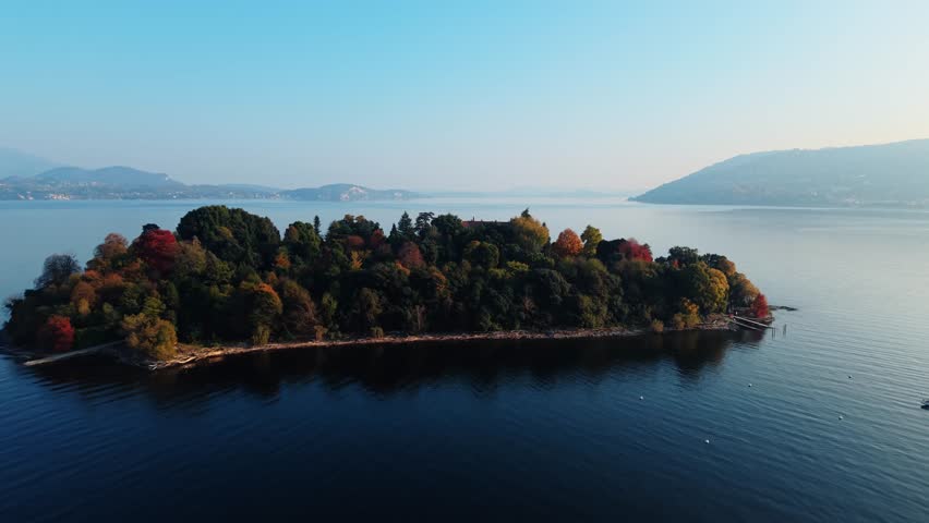 Aerial view of Isola Madre island with colorful trees surrounded by deep blue water under a clear sky, Isola Madre, Stresa, Italy.