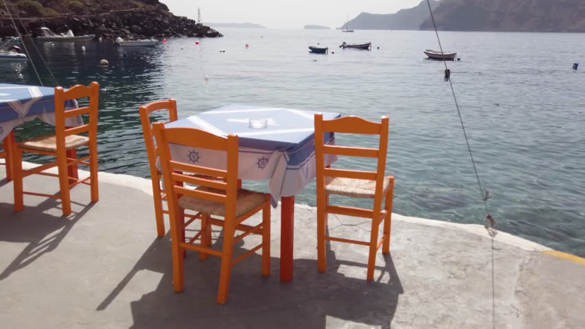 relaxing chairs and dinner table with view of caldera, Santorini, Greece, toned