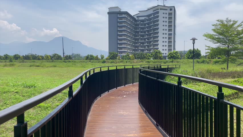 Sunny park walkway with green landscape and blue sky.