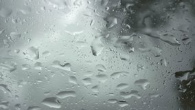 Detailed view of rain drops cascading down a car window during a heavy storm. The dynamic, water-streaked glass creates an abstract backdrop for the dramatic, moody atmosphere. - Powered by Shutterstock - Get 15% off with code: PIKWIZARD15