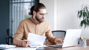 Busy thoughtful businessman analyzing financial documents checking data on laptop while sitting at a workplace in a business office. Financier deals with financial report, thinks over working details - Powered by Shutterstock - Get 15% off with code: PIKWIZARD15