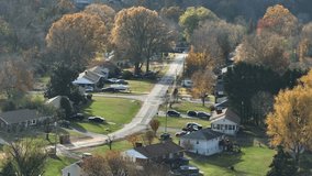 Sweeping aerial drone capture of an American rural suburban area with winding roads, houses and autumn trees, bathed in sunlight, suggesting eco-friendly living and digital connectivity. - Powered by Shutterstock - Get 15% off with code: PIKWIZARD15