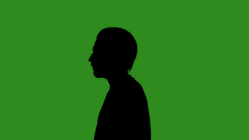 A black, isolated silhouette of a man putting on a cap against a green chroma key background, side view. Minimalistic contrast and modern visual composition, mockup.
