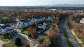 Smooth aerial drone sweep across an American suburban neighborhood, surrounded by autumn woods and winding roads at midday, highlighting peaceful community living with hints of digital connectivity. - Powered by Shutterstock - Get 15% off with code: PIKWIZARD15