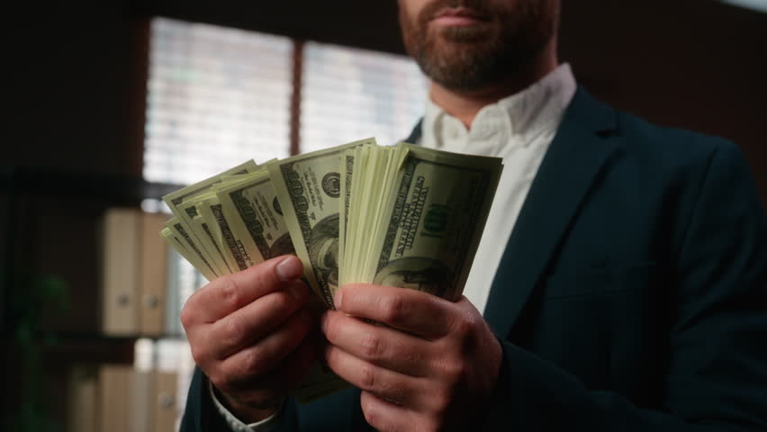 Caucasian middle-aged businessman serious confident male business man holding money counting cash financial success rich businessperson in office finance achieve employer hold dollars count close up
